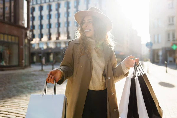 快乐的女游客提着购物袋走过阳光灿烂的欧洲街道 漂亮的女人购物后喜欢天气 消费主义 积极的生活方式 — 图库照片