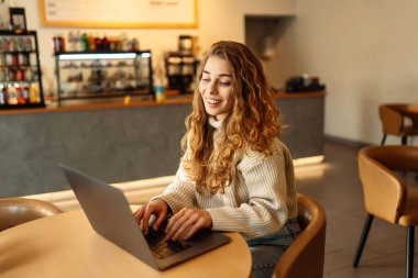 Bir kafede dizüstü bilgisayarda oturan genç bir kadının portresi. İnternette çalışıyor, serbest çalışıyor. Eğitim ve blog dışında. Teknolojiler.