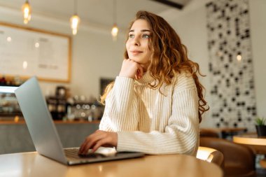 Bir kafede dizüstü bilgisayarda oturan genç bir kadının portresi. İnternette çalışıyor, serbest çalışıyor. Eğitim ve blog dışında. Teknolojiler.