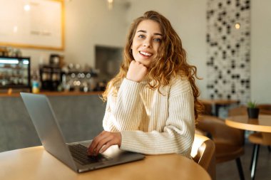 Bir kafede dizüstü bilgisayarda oturan genç bir kadının portresi. İnternette çalışıyor, serbest çalışıyor. Eğitim ve blog dışında. Teknolojiler.