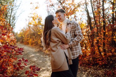 Mutlu çift güneşli sonbahar parkında yürüyüp eğleniyor. Birlikte eğleniyoruz. Yaşam tarzı. Moda, sonbahar modası..