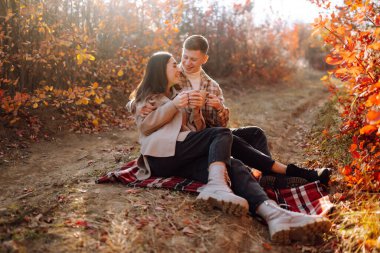 Mutlu çift güneşli sonbahar parkında yürüyüp eğleniyor. Birlikte eğleniyoruz. Yaşam tarzı. Moda, sonbahar modası..