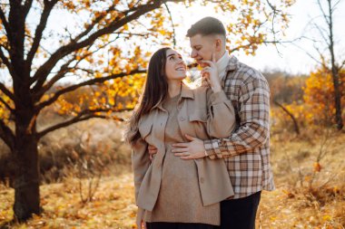 Mutlu çift güneşli sonbahar parkında yürüyüp eğleniyor. Birlikte eğleniyoruz. Yaşam tarzı. Moda, sonbahar modası..