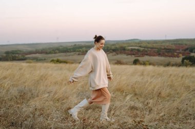 Sonbahar sahasında poz veren şık elbiseli güzel bir manken. Moda konsepti. Yaşam tarzı, eğlence..