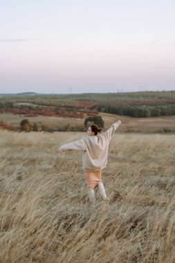 Sonbahar sahasında poz veren şık elbiseli güzel bir manken. Moda konsepti. Yaşam tarzı, eğlence..