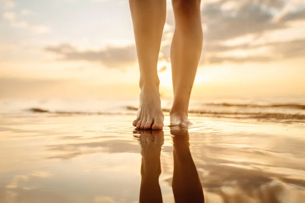 Leg of a young woman walking along the sea on a summer beach. Slim legs. The concept of vacation, travel, freedom.