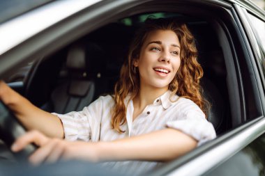Araba süren güzel, gülümseyen bir kadın. Sürücü bir kadın. Açık havada yaz portresi. Araba yolculuğu, yaşam tarzı konsepti..