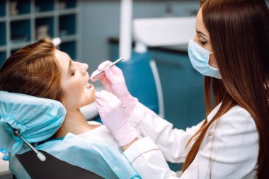 Profesyonel kadın dişçi çalışıyor. Diş ameliyatı sırasında kadın hasta. Diş bakımı. Caries önleme genel değerlendirmesi.