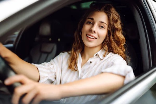 Beautiful smiling woman driving a car. The driver is a woman driving. Summer outdoor portrait. Car travel, lifestyle concept.