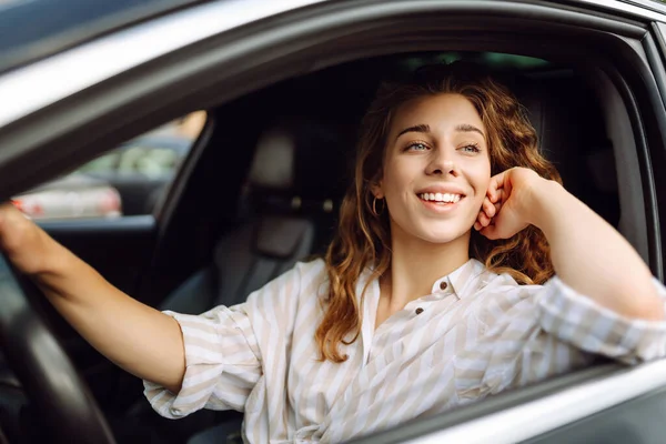 Beautiful smiling woman driving a car. The driver is a woman driving. Summer outdoor portrait. Car travel, lifestyle concept.