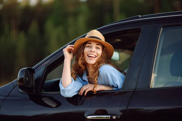 快乐的女旅行家 戴着帽子 享受着车窗上的夕阳西下 汽车旅行 — 图库照片