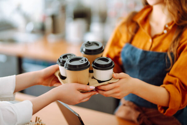 Beautiful barista woman issues coffee orders to go in a coffee shop. Small business owner. Takeaway food and drinks.