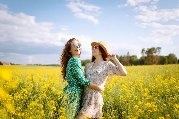 Dwie Wesołe Dziewczyny Ubrane Stylowe Sukienki Przechodzą Przez Kwitnące Pole — Zdjęcie stockowe