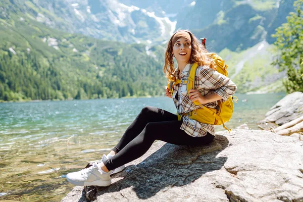 Szczęśliwa Turystka Dużym Żółtym Plecakiem Cieszy Się Widokiem Górskie Jezioro — Zdjęcie stockowe