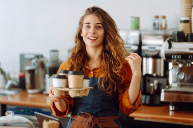 Bir barın arkasında elinde sıcak içecek olan sevimli bir bayan baristanın portresi. Modern kafe. İş konsepti.