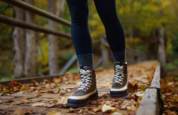 ブーツの女性の足は 秋の森の木製ウォーキングパスに沿っています バケーション旅行コンセプト ハイキングトレイル — ストック写真