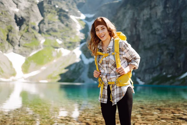 Kobieta Turystka Jasnożółtym Plecakiem Stoi Pobliżu Alpejskiego Jeziora Pośród Górskich — Zdjęcie stockowe