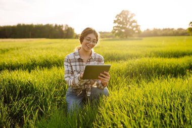Çiftçi kadın modern teknoloji kullanıyor, dijital tablet akıllı çiftçilik için. Ürün büyümesini kontrol ediyorum. Tarım faaliyetleri.