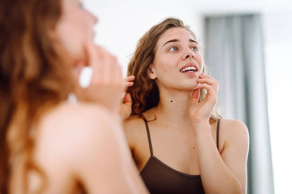 Potret Seorang Wanita Muda Menyentuh Jerawat Wajahnya Saat Melihat Cermin Stok Gambar
