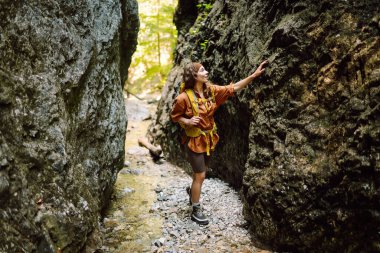 Yürüyüş yapan sarı sırt çantalı bir gezgin yeni yerleri keşfeder, dereden su toplar, dağlara tırmanır ve orman boyunca yürüyüş yapar..