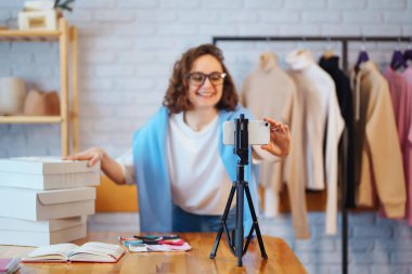 İşyerindeki dijital tabletli mutlu küçük işletme sahibi. Genç bir iş kadını giyim mağazasından siparişleri kontrol ediyor. Alışveriş konsepti, moda.