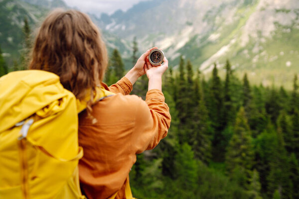 Wanderlust concept. Stylish woman holding a compass in her hand while traveling in the mountains. The concept of hiking, nature.