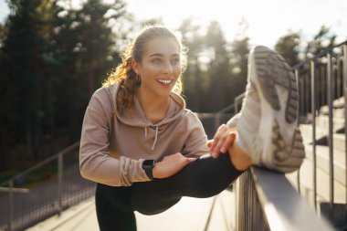 Spor giyimli atletik kadın dışarıda egzersiz yapıyor. Sokakta bir kadın spor için içeri giriyor. Spor anlayışı, spor eğitimi. Antrenör vücut esneme egzersizleri yapar..
