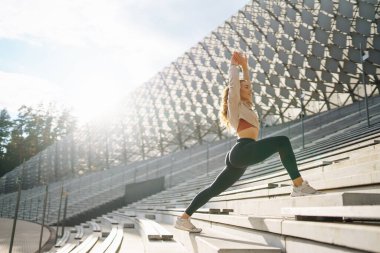Spor giyimli atletik kadın dışarıda egzersiz yapıyor. Sokakta bir kadın spor için içeri giriyor. Spor anlayışı, spor eğitimi. Antrenör vücut esneme egzersizleri yapar..