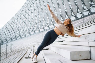 Spor giyimli atletik kadın dışarıda egzersiz yapıyor. Sokakta bir kadın spor için içeri giriyor. Spor anlayışı, spor eğitimi. Antrenör vücut esneme egzersizleri yapar..