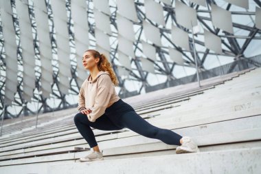 Spor giyimli atletik kadın dışarıda egzersiz yapıyor. Sokakta bir kadın spor için içeri giriyor. Spor anlayışı, spor eğitimi. Antrenör vücut esneme egzersizleri yapar..