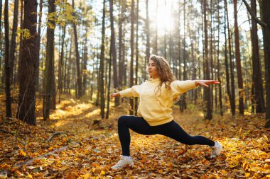 Güzel bir kadın sonbahar ormanında yoga yapıyor. Yaşam tarzı ve meditasyon konsepti.