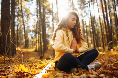 Güzel bir kadın sonbahar ormanında yoga yapıyor. Yaşam tarzı ve meditasyon konsepti.