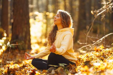 Güzel bir kadın sonbahar ormanında yoga yapıyor. Yaşam tarzı ve meditasyon konsepti.
