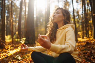 Güzel bir kadın sonbahar ormanında yoga yapıyor. Yaşam tarzı ve meditasyon konsepti.
