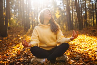 Güzel bir kadın sonbahar ormanında yoga yapıyor. Yaşam tarzı ve meditasyon konsepti.
