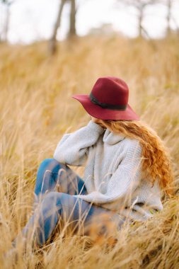 Sonbahar otlağında şapkalı gülümseyen kadın havanın tadını çıkarıyor, dışarıda vakit geçiriyor. Yaşam tarzı, rahatlama ve hafta sonu konsepti.
