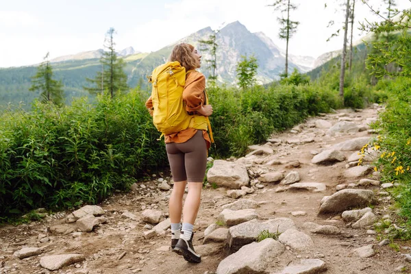 Kobieta Podróżuje Szlakiem Turystycznym Wśród Gór Żółtym Plecakiem Bucikami Turystycznymi — Zdjęcie stockowe