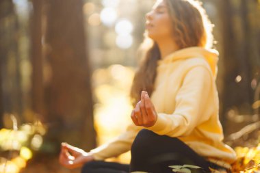 Genç bir kadın sonbahar ormanında, düşmüş yapraklar üzerinde yoga egzersizleri yapıyor. Yaşam tarzı, meditasyon konsepti. Eğleniyorum..