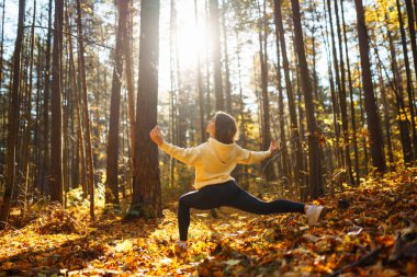 Genç bir kadın sonbahar ormanında, düşmüş yapraklar üzerinde yoga egzersizleri yapıyor. Yaşam tarzı, meditasyon konsepti. Eğleniyorum..