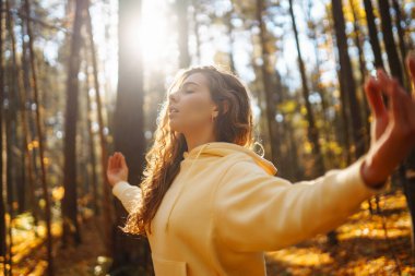 Genç bir kadın sonbahar ormanında, düşmüş yapraklar üzerinde yoga egzersizleri yapıyor. Yaşam tarzı, meditasyon konsepti. Eğleniyorum..