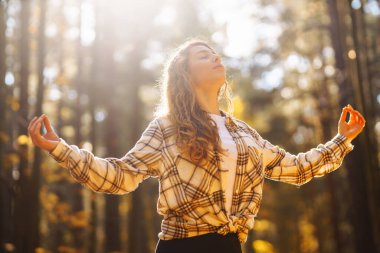 Genç bir kadın sonbahar ormanında, düşmüş yapraklar üzerinde yoga egzersizleri yapıyor. Yaşam tarzı, meditasyon konsepti. Eğleniyorum..