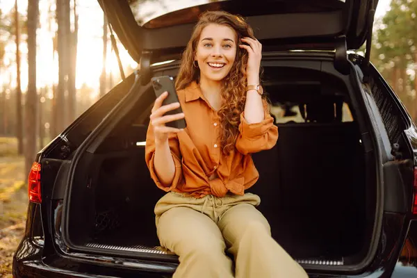 Young Female Tourist Casual Clothes Sits Trunk Car Uses Phone — Stock Photo, Image