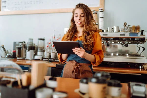 Gülümseyen kadın bardaki tezgahın önünde beklerken panchette 'ten sipariş alıyor. İş konsepti. Tenoloji konsepti, yemek servisi..