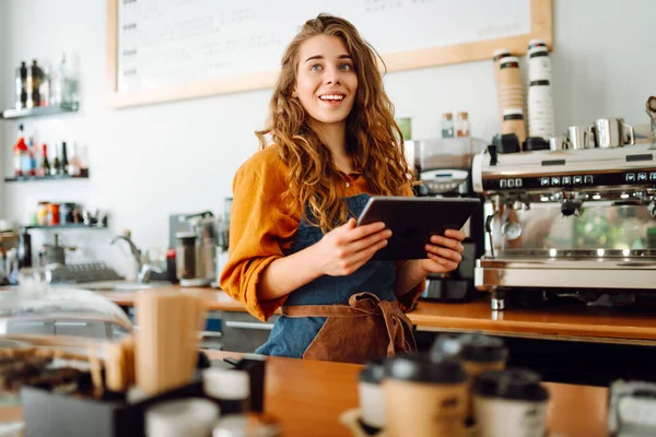 Gülümseyen kadın bardaki tezgahın önünde beklerken panchette 'ten sipariş alıyor. İş konsepti. Tenoloji konsepti, yemek servisi..