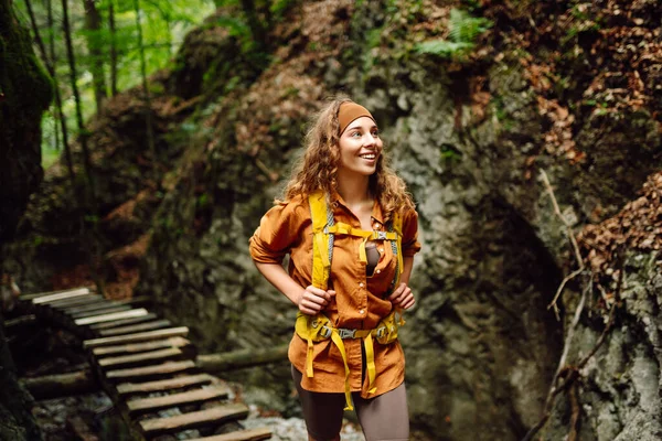 Szczęśliwa Kobieta Pieszych Ubraniach Żółtym Plecakiem Spaceruje Drewnianej Ścieżce Turystycznej — Zdjęcie stockowe