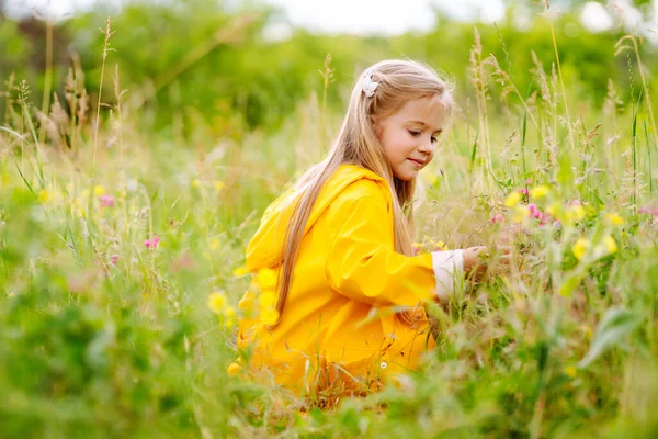 Ένα Κοριτσάκι Κίτρινο Παλτό Διασκεδάζει Μαζεύοντας Αγριολούλουδα Στο Πάρκο Παιδί — Φωτογραφία Αρχείου