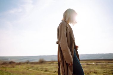 Şık bir kadın dinleniyor, tepede güneşli bir günün tadını çıkarıyor, uçurumdan bakıyor, özgürlüğü hissediyor. Doğa kavramı, rahatlama..