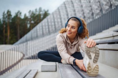 Sokakta egzersiz yapan sporcu bir kadın. Spor giyimli bir kadın spor için içeri girer, güneşli bir günde dışarıda egzersiz yapar. Spor anlayışı, aktivite.