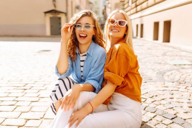Mutlu iki arkadaş şehirde gülümseyerek poz veriyor. Güzel kadınların hafta sonu eğlenirken, seyahat ederken çekilmiş sokak fotoğrafı. Seyahat, macera konsepti.