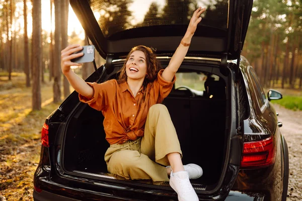 Seorang Wanita Muda Mengagumi Matahari Terbenam Bagasi Mobil Dengan Telepon — Stok Foto